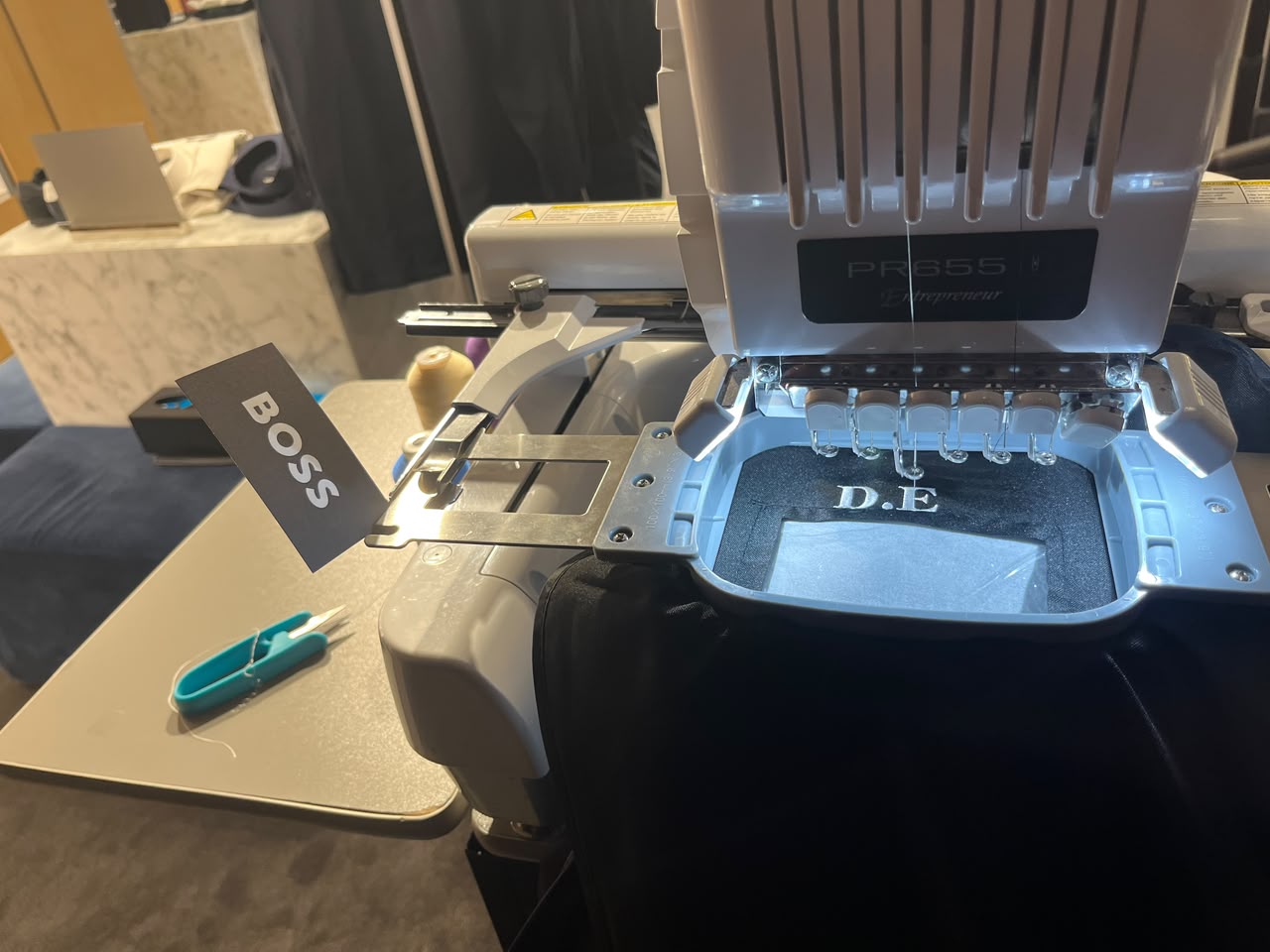 Embroidery machine personalizing a Hugo Boss piece on-site at a brand event